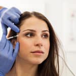 Woman Receiving Botox Injection For Crow’s Feet Treatment