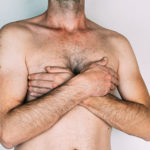 Caucasian man without shirt with hands on chest, isolated on gra